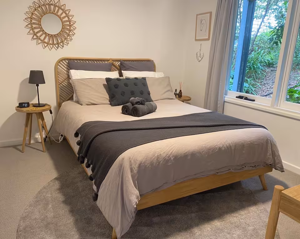 Second bedroom with rattan bedhead and leafy garden outlook